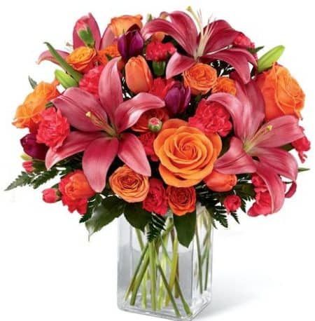 Brilliant orange roses, spray roses and tulips are simply stunning arranged amongst hot pink mini carnations, purple tulips, dark pink Asiatic lilies and lush greens.
