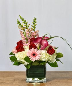 Pink perfection includes red roses, pink flowers, white hydrangea, and greenery