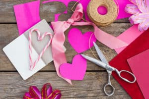 Pink paper, scissors, bows, ribbons, and other arts and craft supplies