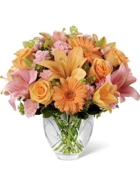 Brighten Your Day Bouquet is blooming with brilliant color and cheer and is sure to lift their spirits with each exquisite bloom. Peach roses, gerbera daisies and Asiatic lilies bring a soft energy to this bouquet when combined with pink mini carnations, pink Asiatic Lilies, bupleurum and variegated pittosporum. Beautifully presented in a designer clear glass vase, this bouquet creates a wonderful way to show them how much you care.