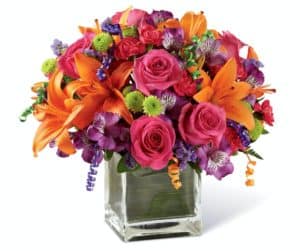 Birthday blooms that are ready to get your recipient's special day started, this flower bouquet is bright, happy, and ready to celebrate! Hot pink roses and orange Asiatic Lilies are vibrant and fun surrounded by purple Peruvian Lilies, hot pink mini carnations, green button poms, purple statice, and an assortment of lush greens. Accented with assorted curling ribbons to give it that party feel and presented in a clear glass cubed vase lined with ti leaf green material for added beauty, this unforgettable birthday bouquet is that ultimate surprise that will make them feel the love on their big day. GOOD bouquet includes 11 stems. Approx. 10"H x 10"W. BETTER bouquet includes 15 stems. Approx. 11"H x 11"W. BEST bouquet includes 19 stems. Approx. 12"H x 12"W. EXQUISITE bouquet includes 23 stems. Approx. 13"H x 13"W.